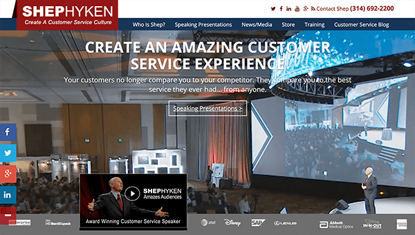Dette er et screenshot af Shep Hyken's hjemmeside. I baggrunden taler han til et stort publikum foran en projektionsskærm. Webstedsteksten siger ”Opret en fantastisk kundeserviceoplevelse. Dine kunder sammenligner dig ikke længere med deres konkurrent. De sammenligner dig med den bedste service, de nogensinde har haft... fra nogen. ”