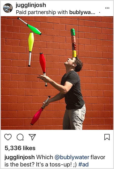 Josh Horton jonglerer klubber, der matcher farverne på fire Bubly vanddåser stablet på hans hoved. Baggrunden er en rød mur. Billedet er en annonce, som Josh oprettede til Bubly-vand og blev sendt i hans Instagram-feed med beskrivelsen Hvilken Bubly-vandsmag er den bedste? Det er en kast op!