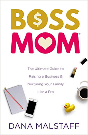Dette er et screenshot af bogomslaget til Boss Mom: The Ultimate Guide to Raising a Business & Nurturing Your Family Like a Pro af Dana Malstaff. Ordene i titlen vises i henholdsvis gul og lyserød. Et dollartegn vises inde i O i ordet Boss. Et hjerte vises inde i O i ordet mor. Coveret har en hvid baggrund, og en notesblok, iPhone, gummiand, en kop kaffe og et åbent rør med lyserød læbestift er arrangeret under titlen og tagline.